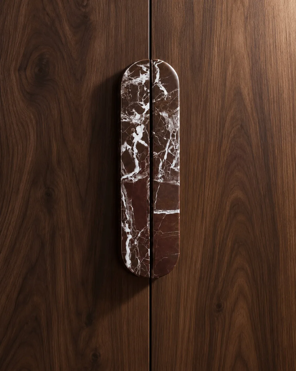 An Oval Pull in red Rosso Levanto marble on a walnut door, up close